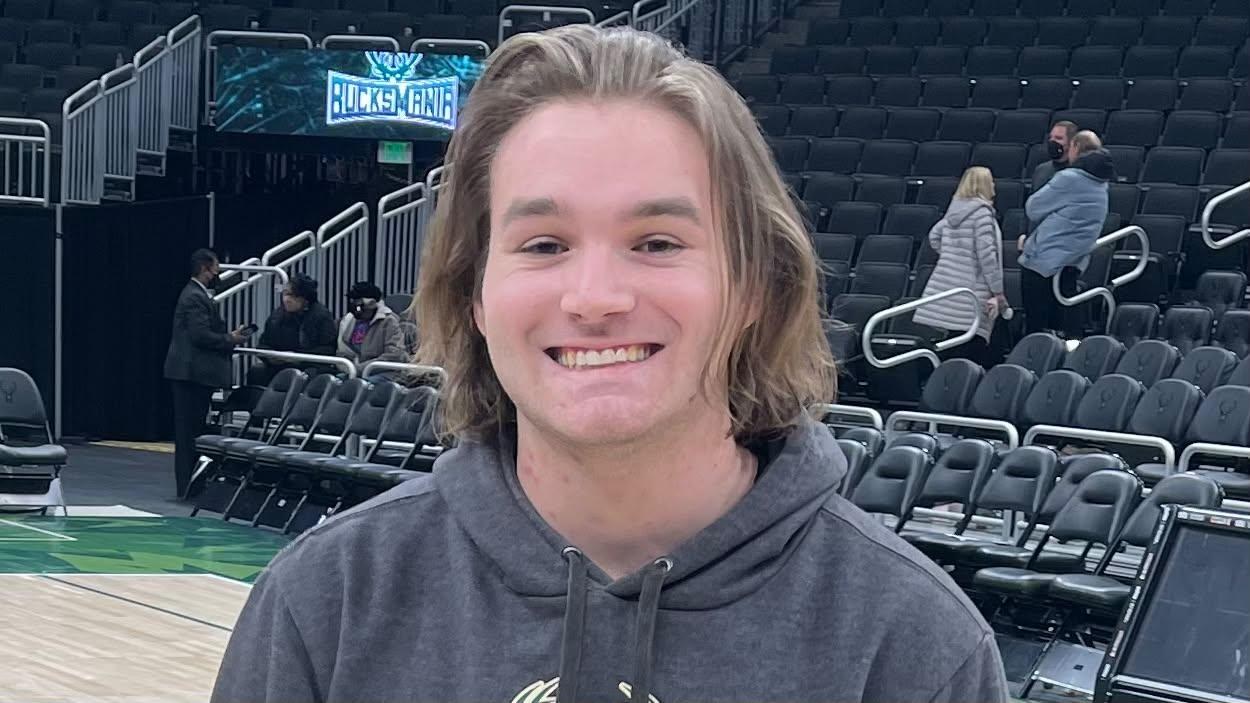 Cole Schmidtknecht smiling courtside
                              at a Milwaukee Bucks game
