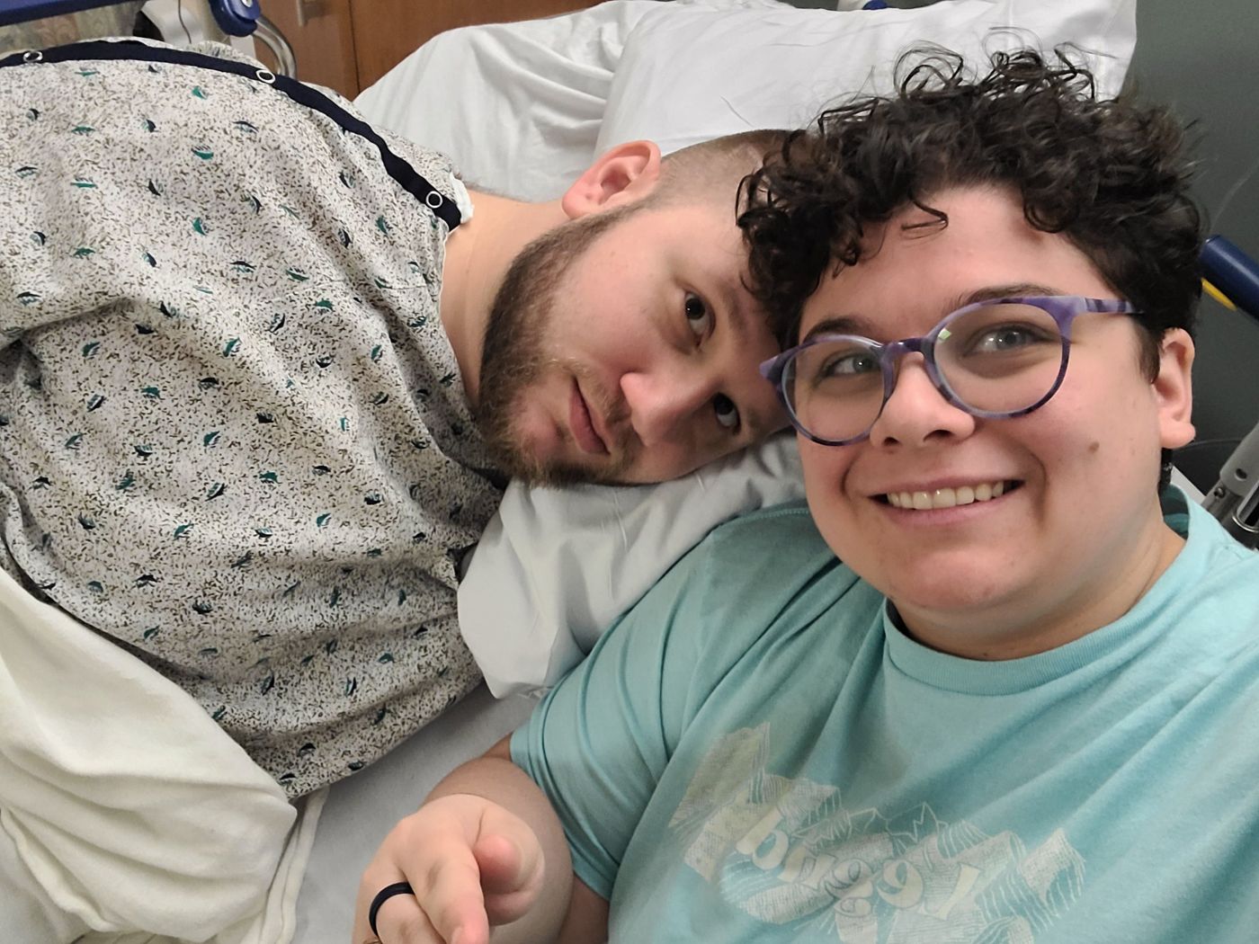 Michael in a hospital bed with his wife Kate beside him